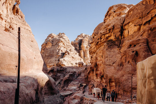 Ruins of the ancient city of Petra in Jordan. Red sandstone mountains on a clear day. Caves in the rock. Tourists in Petra. Colorful photos.