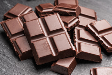 Pieces of milk chocolate bar on gray background. Sweet food is made of cocoa and sugar.