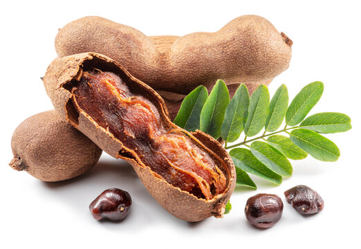 Ripe tamarind fruit, leaves and some tamarind seeds isolated on white background.