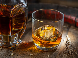 Carafe of whisky and glass of whisky on old wooden cask at the dark background.