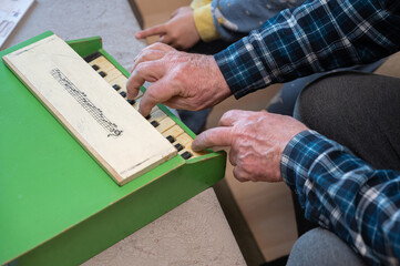 A grandfather teaches his grandson to play the toy piano.