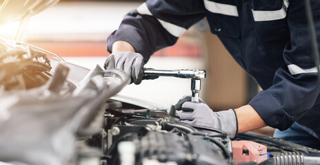 Obraz premium Mechanic works on the engine of the car in the garage. Repair service. Concept of car inspection service and car repair service.