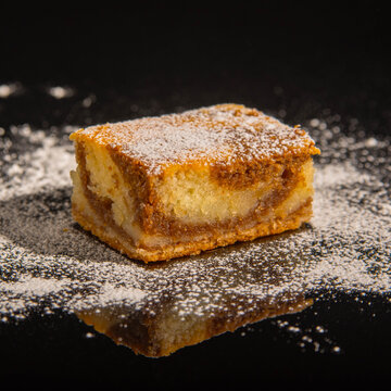 Besquit, cake on a black background, sprinkled with powdered sugar, dark and light layer of beckett on a black background, copy space