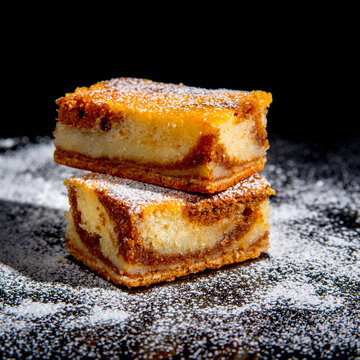 Besquit, cake on a black background, sprinkled with powdered sugar, dark and light layer of beckett on a black background, copy space