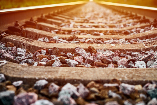 Railway track line in sunlight, railroad train track landscape with ballast gravel and crushed stone