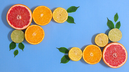 Creative copy space background with sliced fresh exotic citrus fruits on cyan theme with grean leaves. Flat lay tropic food concept
