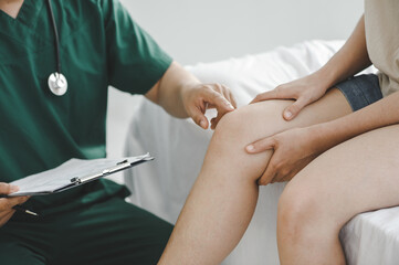 patient is consulting a therapist and explaining with injured leg or knee after the accident and...