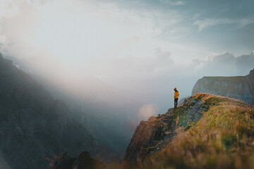 Hiker woman standing on mountain ridge achieving the top. Successful woman hiker looking at view...