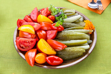 Raw Food - Fresh Vegetable Plate. Plate with healthy organic food on grey table. Tomato, Celery, Cucumber and Radish Vegetable and Fresh Greens.