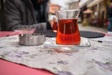 Traditional tea, turkish tea and ashtray on table. Blurred people and selective focus photo.