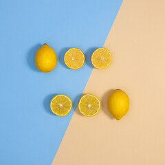 Cretive layout with whole and sliced organic lemon on pastel blue and beige background. Flat lay minimal cistrus food composition