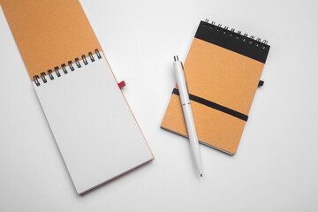 Top view of open spiral blank notebook with pen on white desk background. Isolated on gray backdrop.