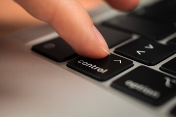 Obraz premium Hand pressing control key on modern laptop keyboard. Control sign and symbol close-up