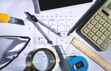 Architects workplace with architectural project plan and other objects.