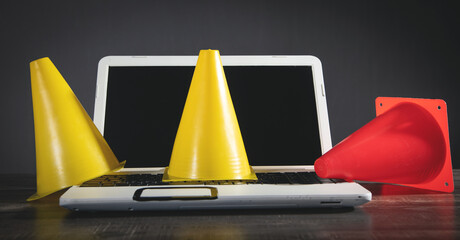 Yellow and red traffic cones on laptop keyboard.