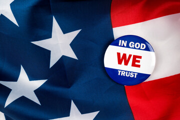 in god we trust text quote on election button laying on the star spangled banner. united states of america concept.