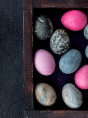 pink, blue and grey colored eggs for Easter, lying in a wooden box