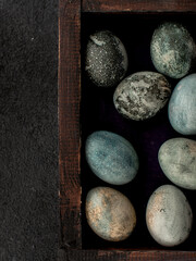 blue and grey colored eggs for Easter, lying in a wooden box