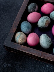 pink, blue and grey colored eggs for Easter, lying in a wooden box