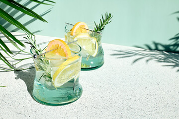 Summer refreshing lemonade drink or alcoholic cocktail with ice, rosemary and lemon slices on...