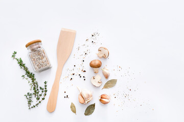 Wooden spatula with spices and vegetables on light grey background, top view.