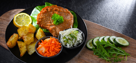 Pork cutlet coated with breadcrumbs with potatoes and salads