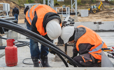 Two electrician builder workers installing high-voltage cable