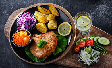 Pork cutlet coated with breadcrumbs with potatoes and salads