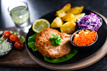 Pork cutlet coated with breadcrumbs with potatoes and salads