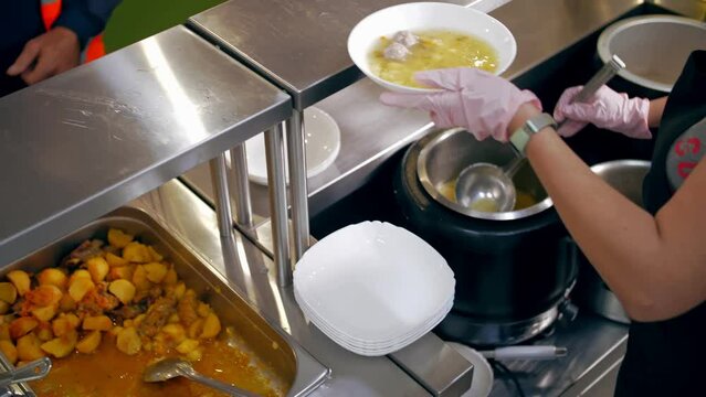 buffet restaurant. self-service cafeteria. close-up. waitress, in protective gloves, pours hot soup into a bowl for a customer. cooking. health food.