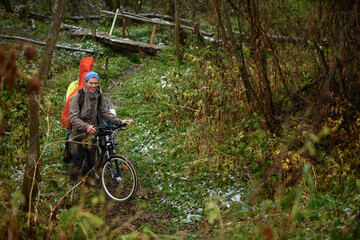 Tourists pushing bicycle in hill in frost autumn forest