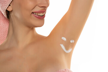 Obraz na płótnie Canvas Beautiful happy woman posing with smile shaped cosmetics product on her underarm isolated on white