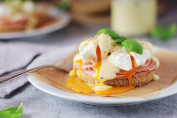 Egg benedict sandwiches - muffin with poached egg, ham and hollandaise sauce	