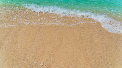 Fototapeta na wymiar Sand beach seaside with white foamy and blue waves from the sea