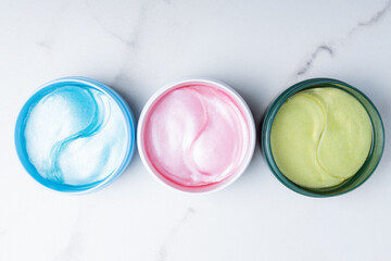 Set of pink, blue and green hydrogel patches for eyes on marble background. Cosmetology, self-care, health care. Close up.