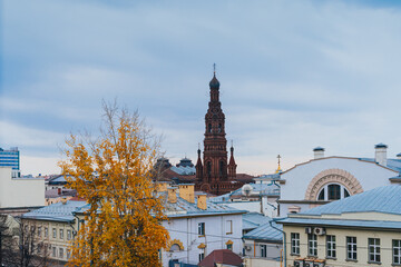 Fototapeta na wymiar The bell tower of the Epiphany Cathedral amidst the rooftops of the old town centre. An autumn landscape. A popular tourist attraction. Kazan, Tatarstan, Russia 