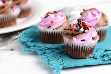 closeup valentines day cupcakes with heart shaped sprinkles on a blue napkin