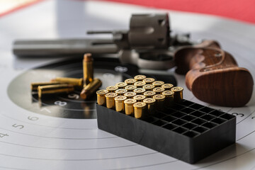 Revolver gun and bullets on background of the target