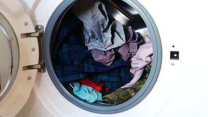 Close-up of a washing machine with the opened front door and clothes in it