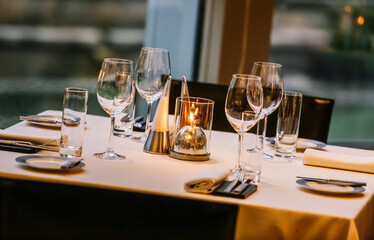 Beautifully set dinner table in a restaurant. Romantic fine dining table with cutleries, plates, wine glasses, napkins and naperies on the table.