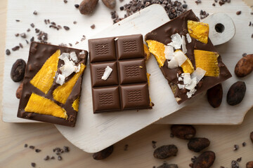 Raw Vegan Handmade Chocolate with dried mango fruits and coconuts slices close up. Chocolate bar with mango on a light background