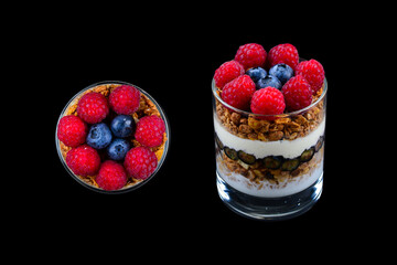 Healthy blueberry and raspberry parfait in a glass on a black background. Two portions. Space for...
