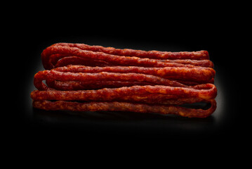 Cabanossi, dry sausage isolated on black background.