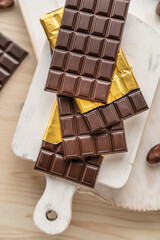 Chocolate bars with open gold cover. Stack of chocolate bars with cacao beans. Flat lay composition with delicious chocolate isolated on white background. Space for text