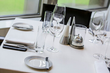 Beautifully set dinner table in a restaurant. Romantic fine dining table with cutleries, plates, wine glasses, napkins and naperies on the table.