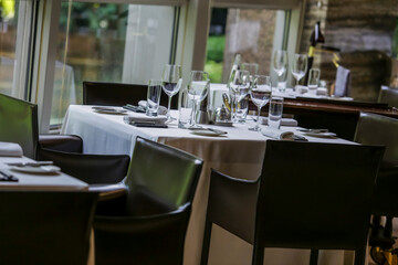 Beautifully set dinner table in a restaurant. Romantic fine dining table with cutleries, plates, wine glasses, napkins and naperies on the table.