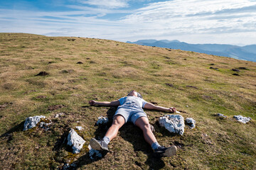 Jovem turista cansado e deitado na grama a descansar em Ainhoa no País Basco - obrazy, fototapety, plakaty