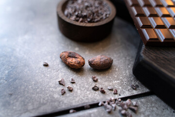 Close up Organic cocoa beans on a black background with a chocolate bar. cooking background, top view