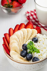 Close up of cottage cheese and fruits bowl on a white table