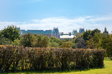 Fototapeta premium Fresh bushes and trees with green leaves on the grand palace in Tsaritsyno and blue sky background. Sunny summer day in a park 
